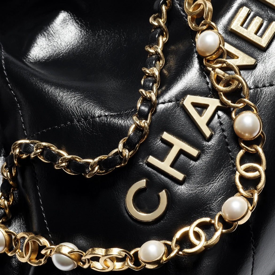 CHANEL 22 Pearl Handbag，黑色亮面小牛皮，珍珠鏈條與雙用背法設計，完美平衡時尚與功能。
